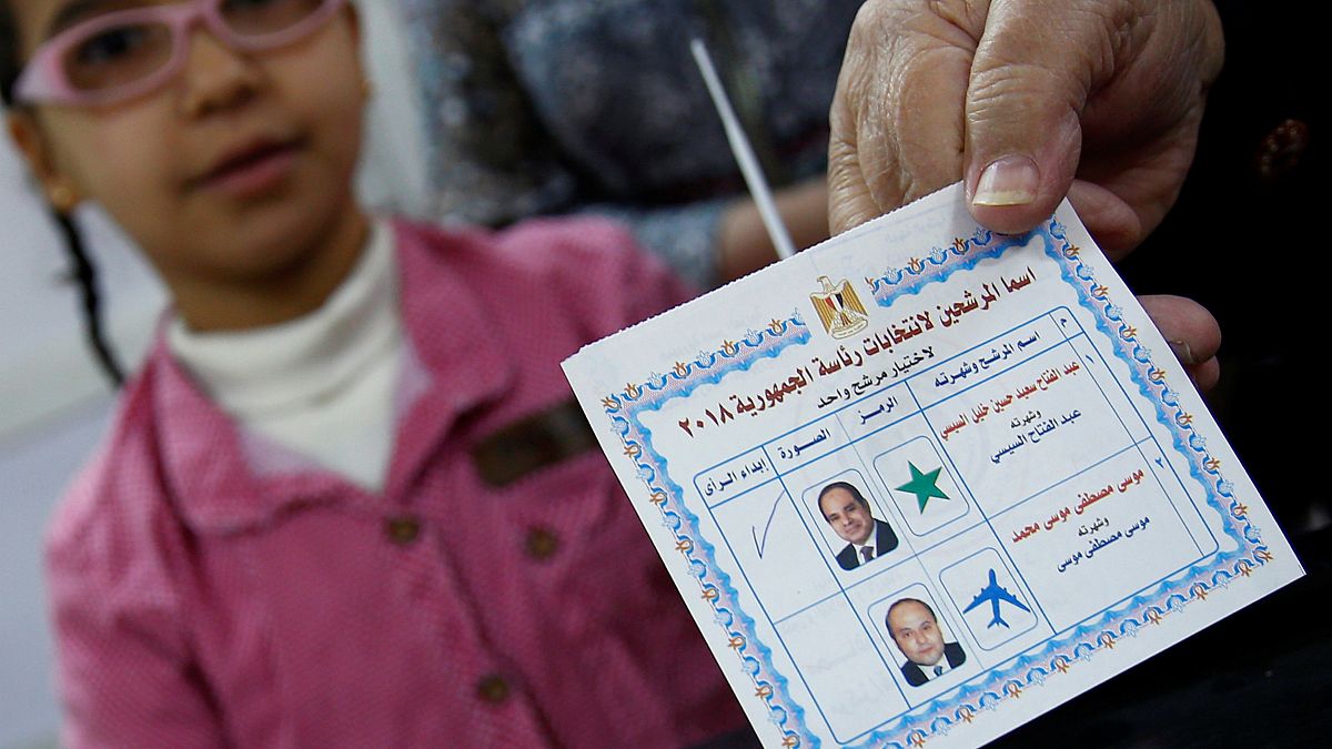 Una donna, in compagnia della figlia, mostra la tessere elettorale egiziana