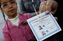 Una donna, in compagnia della figlia, mostra la tessere elettorale egiziana