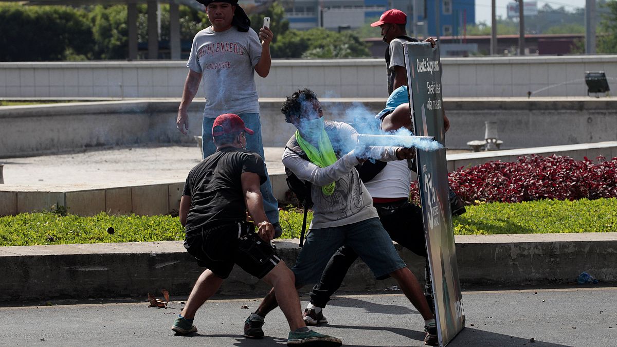 A demonstrator fires a homemade mortar towards riot police during protest