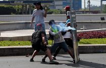 A demonstrator fires a homemade mortar towards riot police during protest