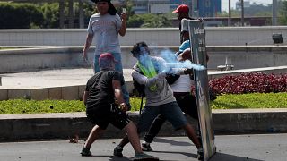 A demonstrator fires a homemade mortar towards riot police during protest
