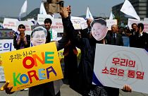 People hold hands as they wear masks of South Korea's President Moon Jae-in