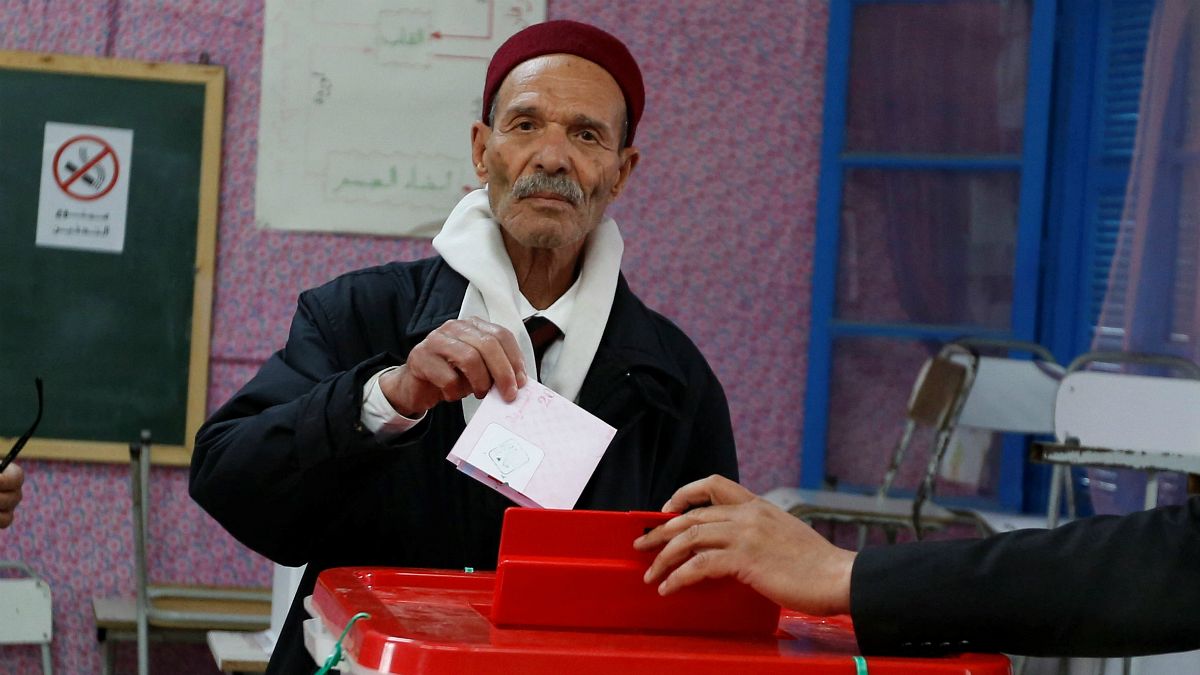 Um tunisino deposita o voto numa urna de Tunis