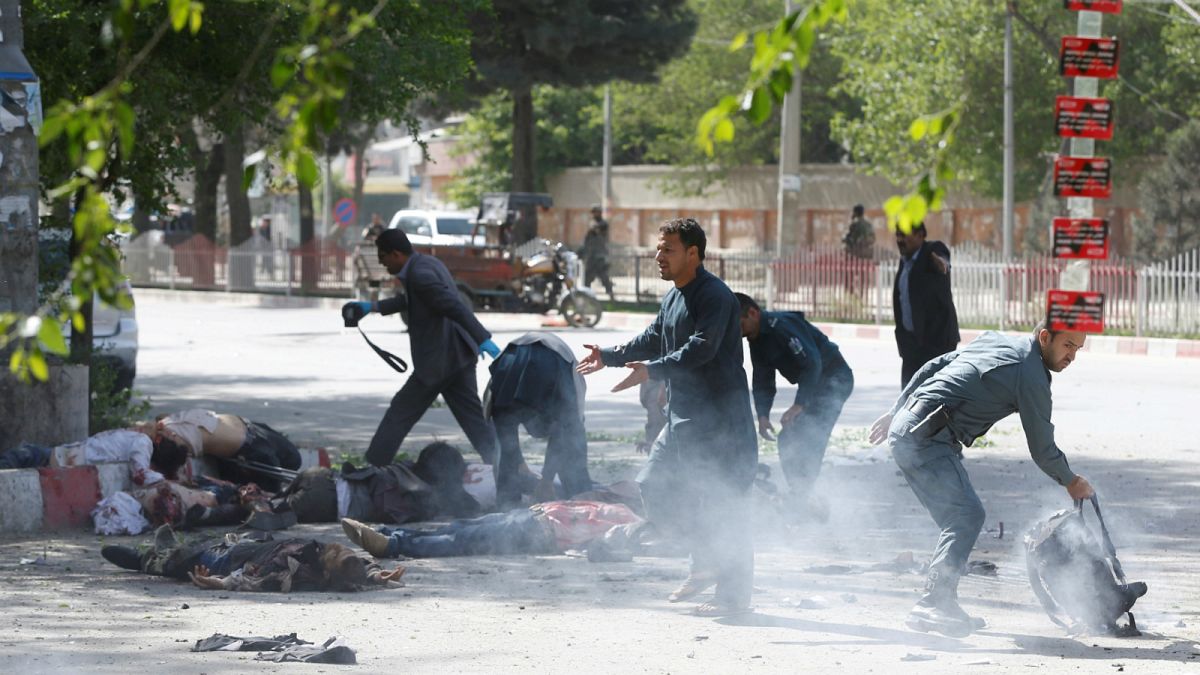 عنصر من الشرطة يساعد صحفي أفغاني بعد تفجير في العاصمة كابول الأسبوع الماضي