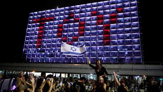 TOY-Lichtprojektion auf ein Hotel in Tel Aviv; Israel-Flaggenschwenkerin
