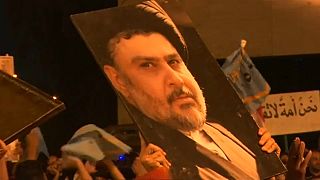 Supporters of Iraqi cleric Moqtada al-Sadr brandish a giant poster 