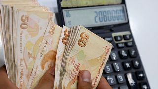 Un cambiavaluta turco conta un fascio di banconote da 50 lire turche