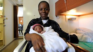 A woman,who just gave birth on board the Aquarius, poses with her newborn