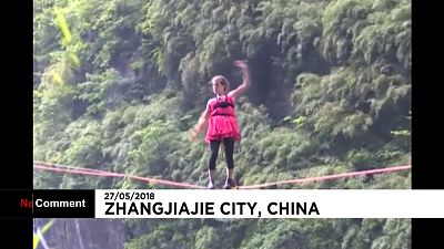 A woman in high-heels walks a highline in China's Hunan province