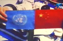 Chinese astronaut holds up the flags of the United Nations and China
