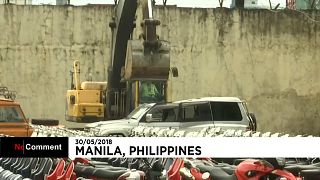 A bulldozer crushes luxury cars in the Philippines