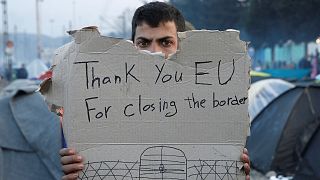 A refguee holds a message at the Greek/Macedonian border