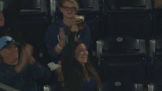 A baseball fan celebrates catching the ball with her beer