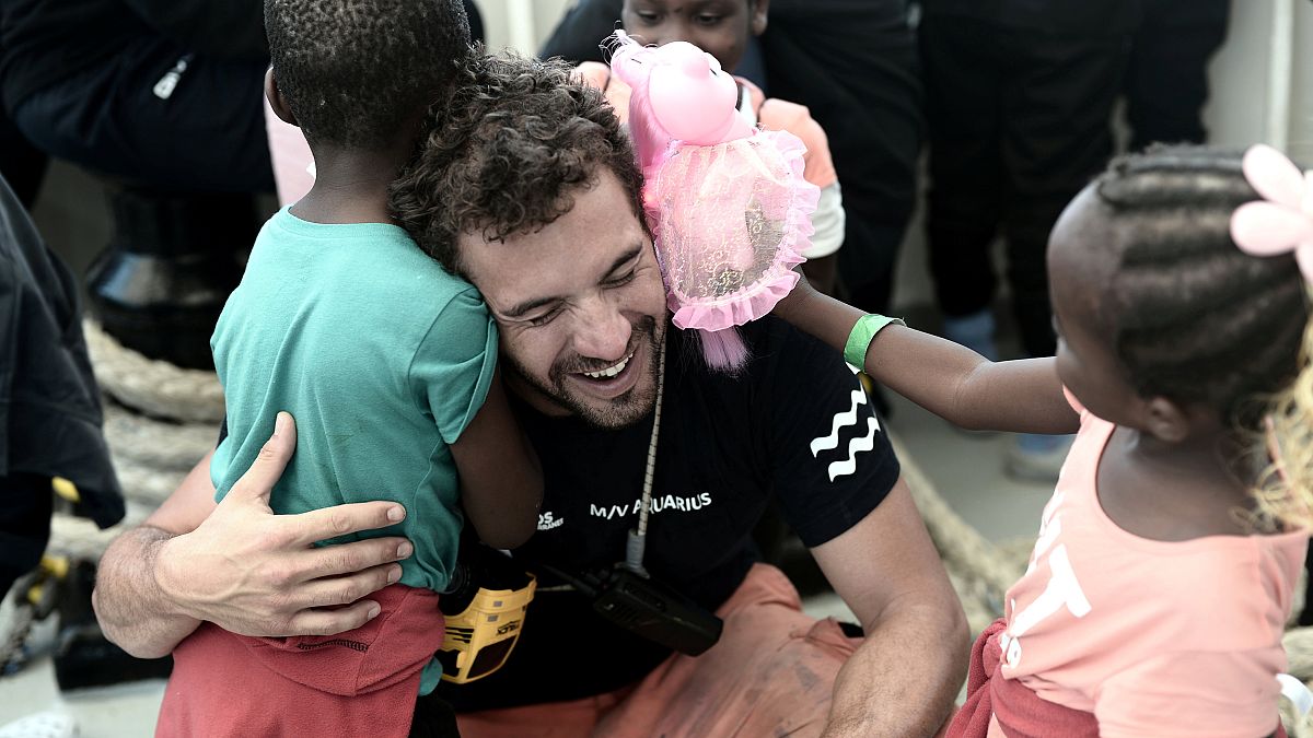A crew member hugs a migrant child aboard the Aquarius rescue ship