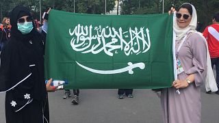 سعوديتان يرفعان علم المملكة خارج استاد لوجنيكي في موسكو