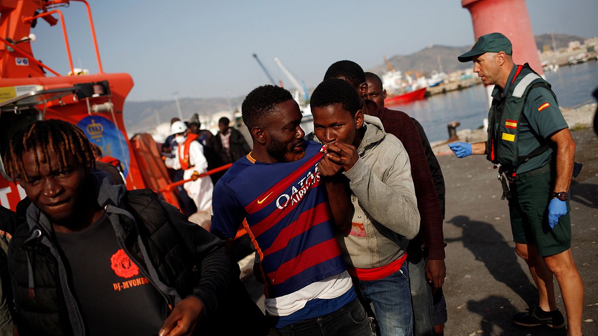 A migrant kisses a Barcelona jersey after arriving on a boat in Motril