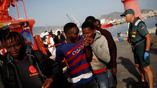 A migrant kisses a Barcelona jersey after arriving on a boat in Motril