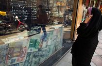 Une femme regarde les taux de change dans une boutique à Téhéran. 