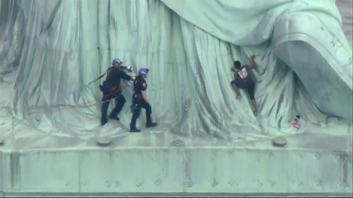Una mujer escala la Estatua de la Libertad para protestar contra Trump