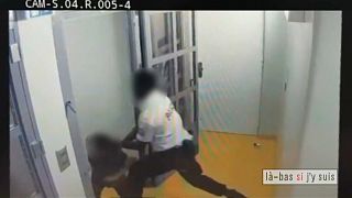Ein Polizist drangsaliert einen Angeklagten im Türrahmen einer Zelle