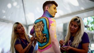 فنانتان ترسمان على جسد رجل خلال مهرجان عالمي سنوي للرسم على الأجساد