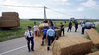 Police clear bales of straw from the path of the Tour de France