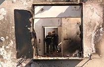 Des pompiers visitent une maison détruite par les incendies en Grèce