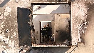 Des pompiers visitent une maison détruite par les incendies en Grèce