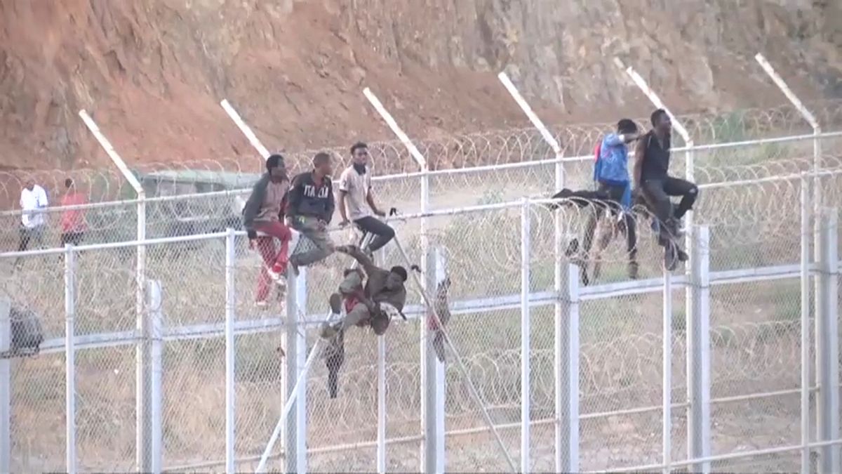 مهاجرون يتسلقون السور الحدودي