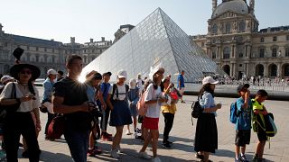 سياح صينيون أمام هرم متحف اللوفر في العاصمة باريس