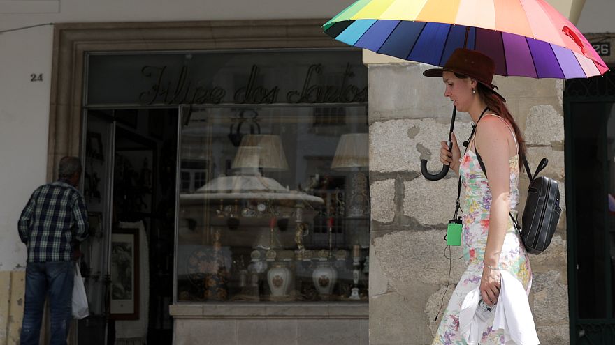 Turista passeia protegida por uma sombrinha em Ã‰vora