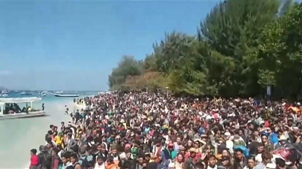 Menschen warten am Strand auf ihre Rettung Menschen warten am Strand auf ihre Rettung
