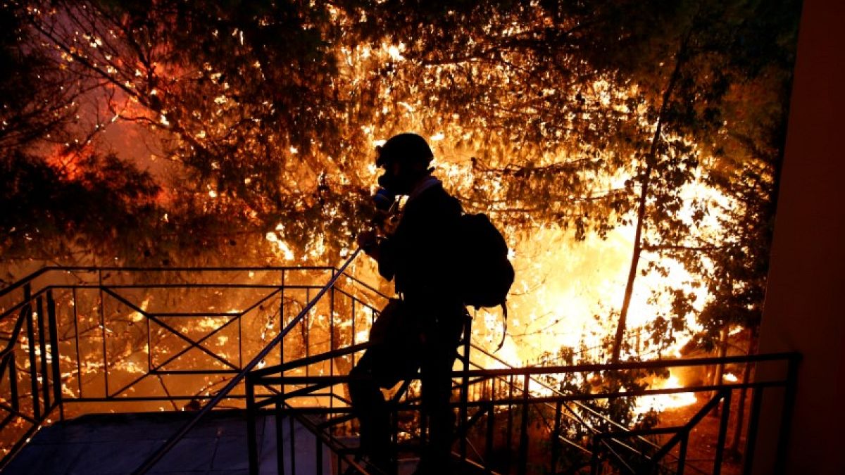 متطوع يرش المياه على حريق غابات في بلدة رافينا قرب أثينا في اليونان ي