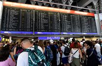 Reisende warten am Flughafen Frankfurt vor der Anzeigetafel