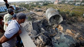 فلسطينيون ينظرون إلى الدمار الذي سببه القصف الإسرائيلي ببلدة المغراقة بغزة