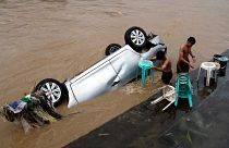 Einwohner reinigen Stühle neben einem überfluteten Auto