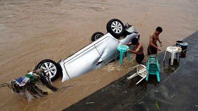 Einwohner reinigen Stühle neben einem überfluteten Auto