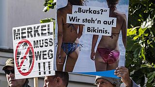"Burka? Biz bikiniyi tercih ederiz" ve "Merkel ayrılmalı" yazılı posterler
