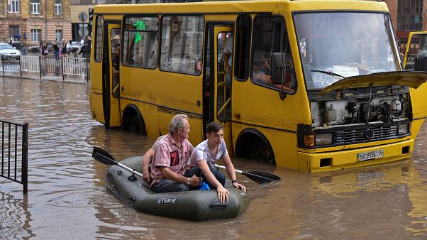 Paddelboot vor gelbem Bus auf überfluteter Straße Paddelboot vor gelbem Bus auf überfluteter Straße