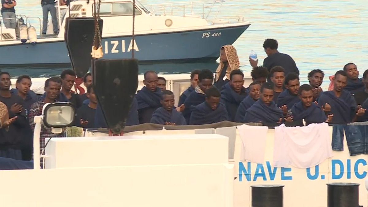 مهاجرون عى سفينة في ميناء كتانيا بإيطاليا ينتظرون إنزالهم 