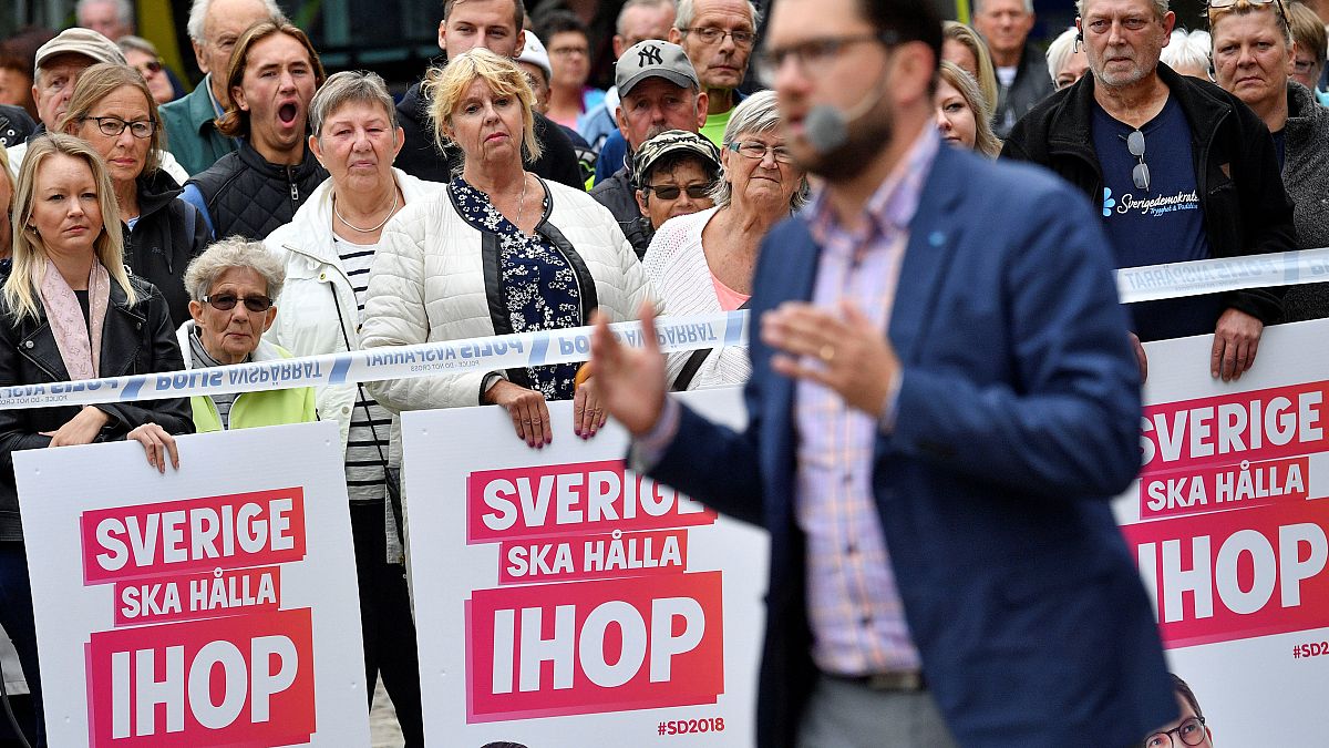 Voters look on as Sweden Democrats leader Jimmie Akesson gives a speech