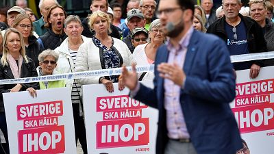 Voters look on as Sweden Democrats leader Jimmie Akesson gives a speech