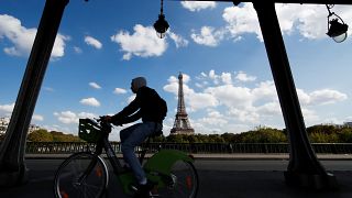 Un hombre cruza un puente en bicicleta cerca de la Torre Eiffel en París