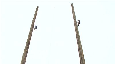 Zwei Männer klettern an Pfählen hoch