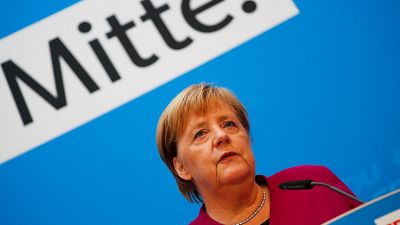 Angela Merkel bei einer Rede; im Hintergrund das Wort "Mitte"