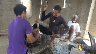 صورة حرفيين يصنعان خنجراً من شظايا القذائف والصواريخ في محافظة حجة باليمن