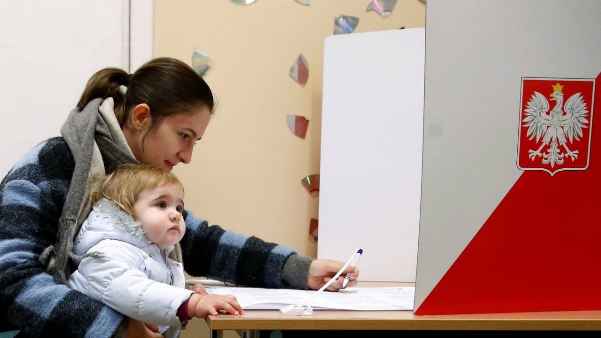 Mãe e filho numa mesa de voto das autárquicas polacas