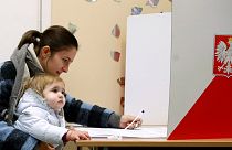 Mãe e filho numa mesa de voto das autárquicas polacas