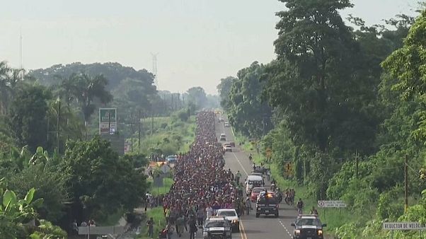 Tausende zentralamerikanische Migranten laufen auf einer Straße. Tausende zentralamerikanische Migranten laufen auf einer Straße.