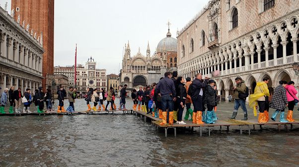 Tourists walk in a flooded Saint Mark Square Tourists walk in a flooded Saint Mark Square